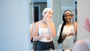 two teen girls looking in mirror putting on cream